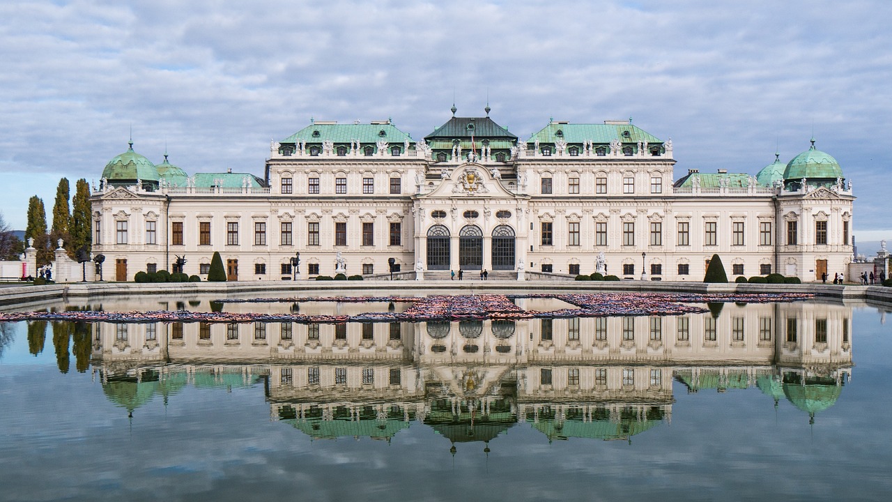 Stunning view of the historic Belvedere Palace in Vienna, Austria, showcasing its Baroque architecture, well-manicured gardens, and reflecting pool under a clear blue sky